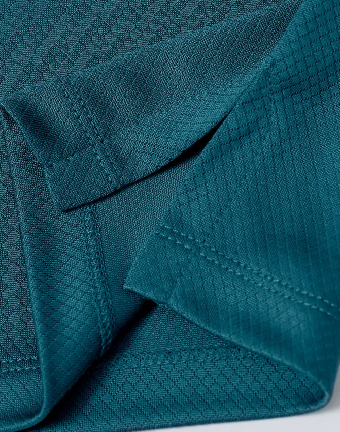 A close-up of a teal fabric featuring a jacquard knit pattern, showing the texture and stitching details.