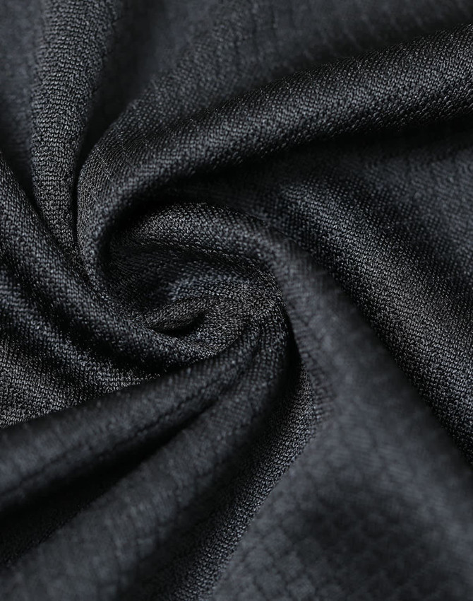 A close-up of black jacquard knit fabric, displaying a textured swirl pattern with a smooth finish.