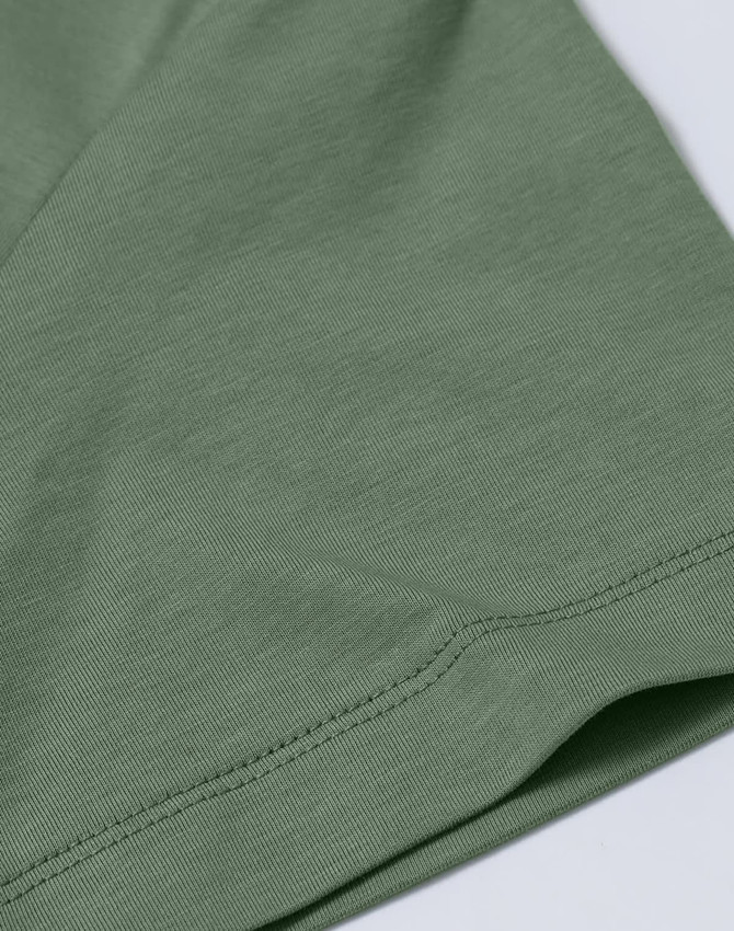 A close-up of a ladies' premium cotton short sleeve tee shirt in a muted green colour, featuring a logo.