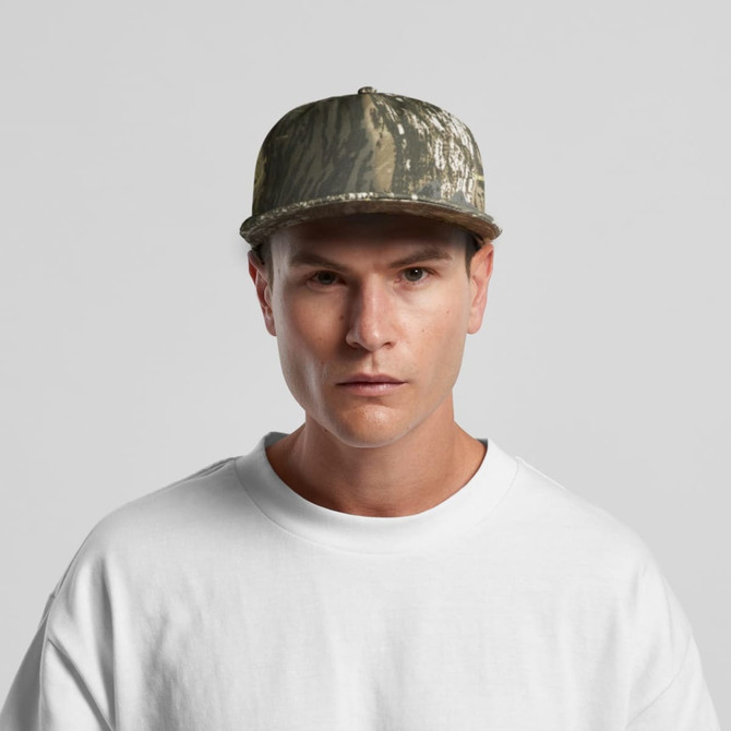 A camo cap featuring a green and brown pattern, worn by a model in a white shirt, with a visible logo.