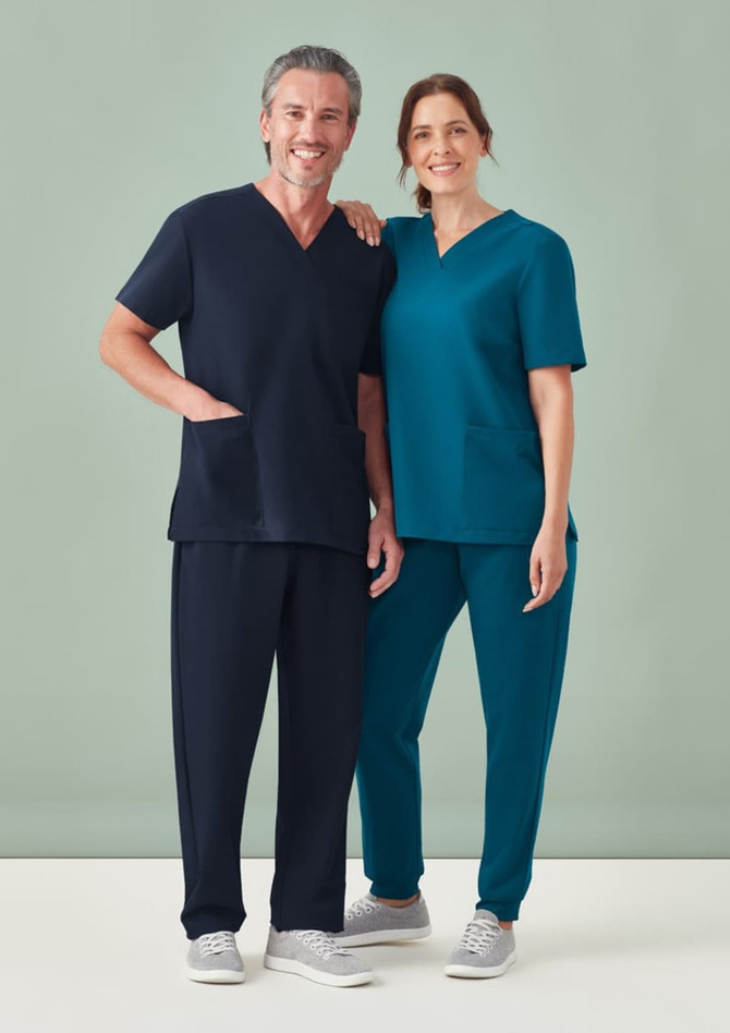 A pair of people wearing scrubs; one in navy jogger pants and the other in teal scrub top and pants. Both have a logo.