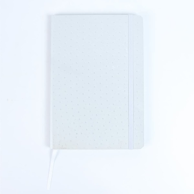 A white notebook with a dotted pattern, featuring a ribbon bookmark and an elastic band closure.