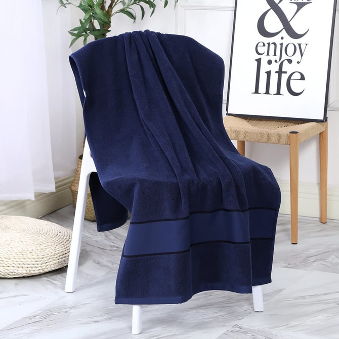 A navy blue bath towel draped over a white chair, with a decorative sign and plant in the background.