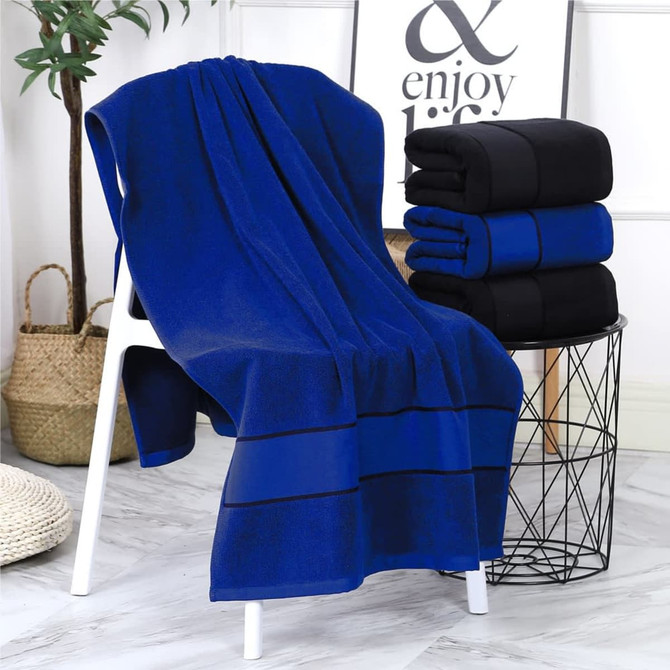 A blue bath towel draped over a white chair beside a stack of black towels and a decorative basket.