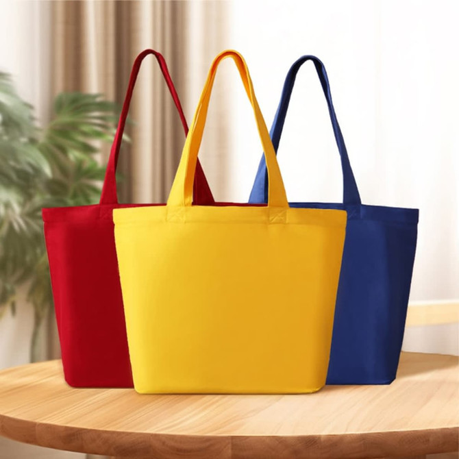 Three tote bags in red, yellow, and blue, featuring handles and a solid colour design.