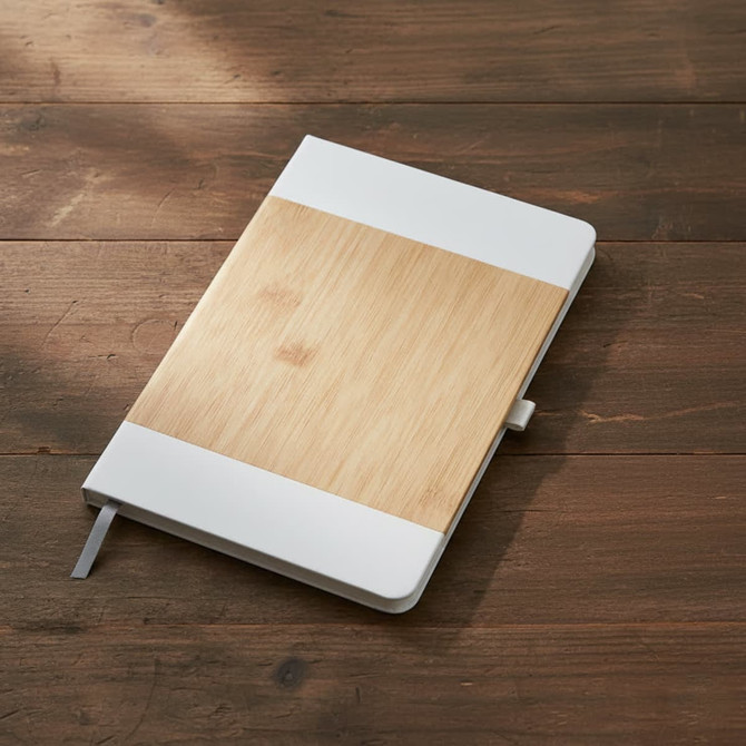 A notebook with a bamboo cover and white accents, placed on a wooden surface. It features a logo.