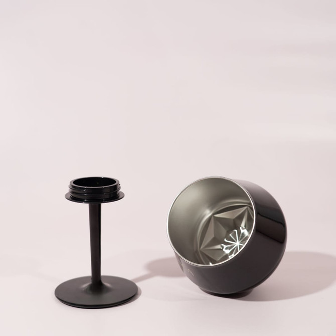 A black, detachable wine glass with a broad bowl and a separate stem. It features a logo on the base.