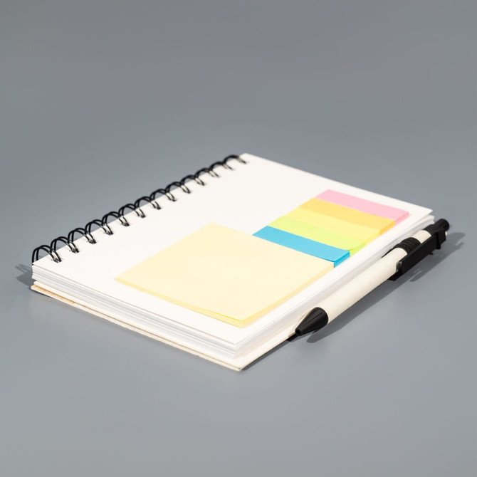 A spiral-bound notebook with blank pages, accompanied by yellow, pink, and green sticky notes and a black pen.