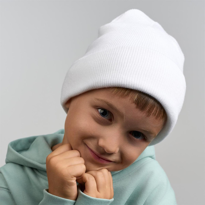 A white beanie made from recycled polyester, worn by a smiling child in a green hoodie.