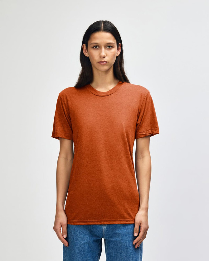 A model wearing an orange American Apparel tri-blend t-shirt, standing against a neutral background.
