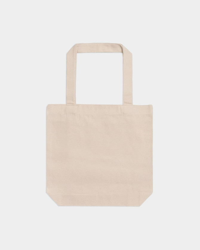 A beige American Apparel tote bag with two shoulder straps and a plain design. It features a logo on one side.