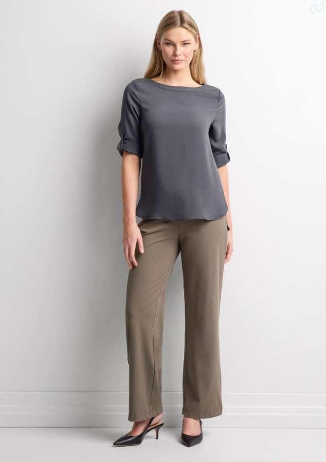A woman stands wearing grey soft stretch pants and a grey top, complemented by black high heels against a neutral background.