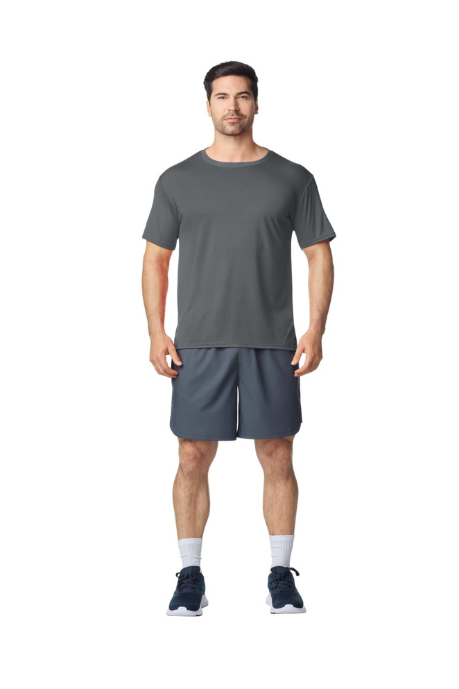 A grey Gildan Performance adult t-shirt displayed on a model, paired with dark sports shorts and shoes.