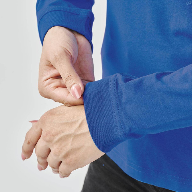 A close-up of a person's hands adjusting the sleeve of a blue long-sleeve T-shirt. The shirt has a logo.