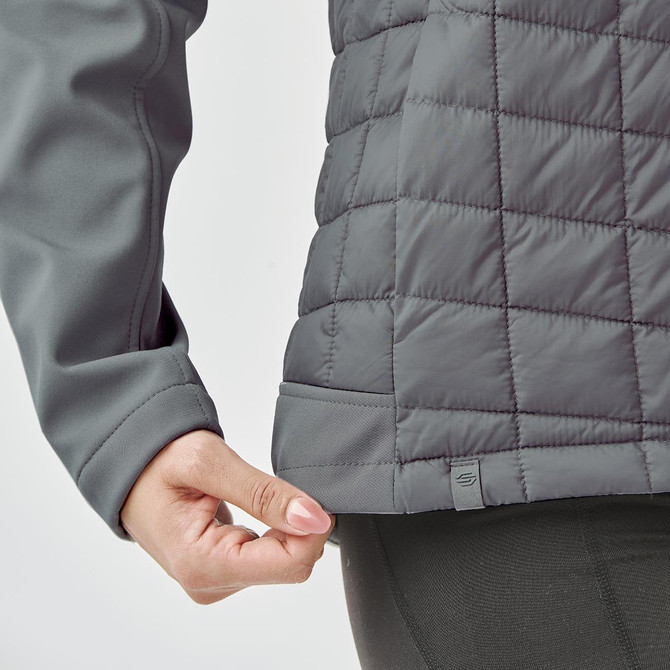 A grey women's thermal softshell jacket featuring a quilted design and a logo at the hem.