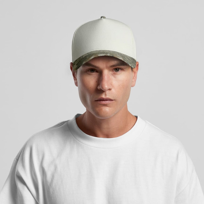 A two-tone camo cap featuring a cream body and a camouflaged brim, worn by a model.