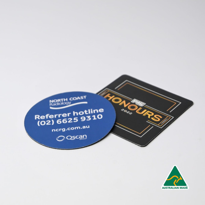 Two round and square coasters, one blue with a logo and contact details, and one black with text, featuring a logo.