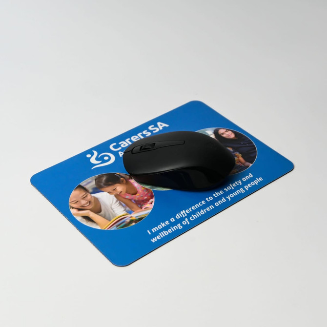 A black mouse positioned on a blue mouse mat featuring images of children and text related to wellbeing.