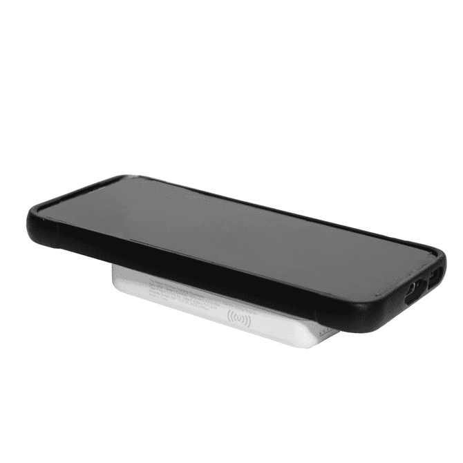 A wireless charging power bank in white with a sleek design supporting a black smartphone on top.