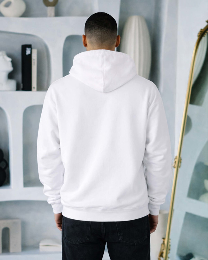 A white hoodie is worn by a person seen from the back, with a styled interior in the background.