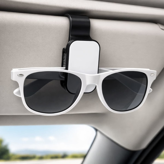A black and white car visor sunglass holder with sunglasses attached, mounted on a car's visor.