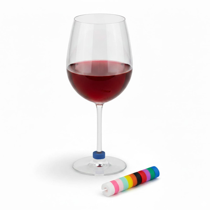 A red wine glass with a blue wine glass marker beside a roll of colourful markers. The glass is elegantly shaped.