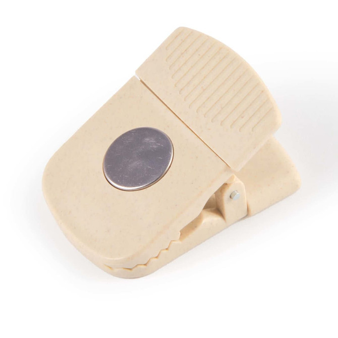 A beige magnetic clip with a textured grip and silver circular accent, featuring a logo.