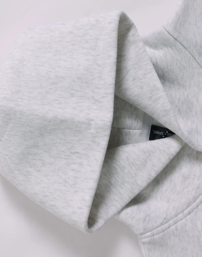 A grey oversized hoodie featuring a hood and a label inside, with a soft fleece texture.