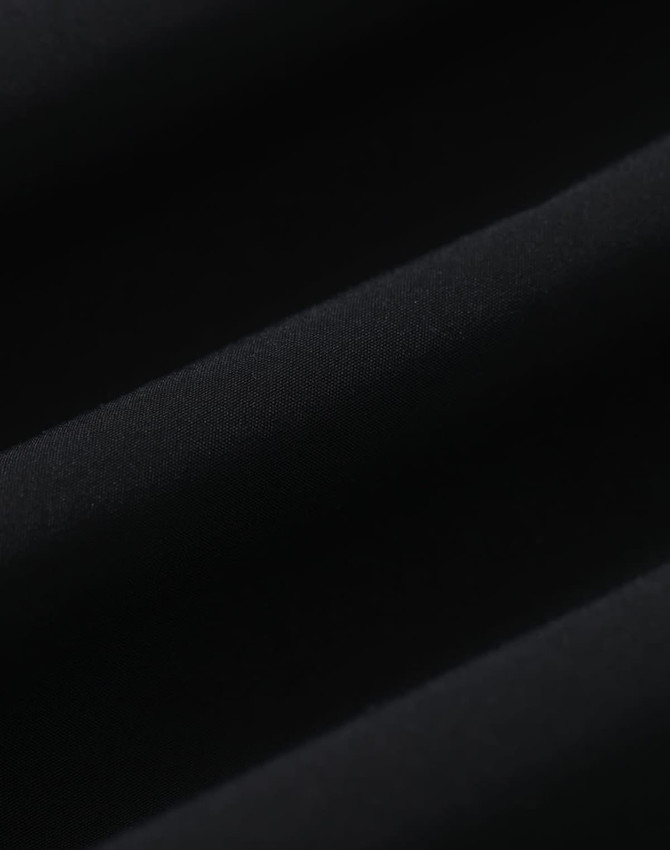 A textured black fabric, showcasing a smooth and soft surface, likely part of a waterproof jacket.
