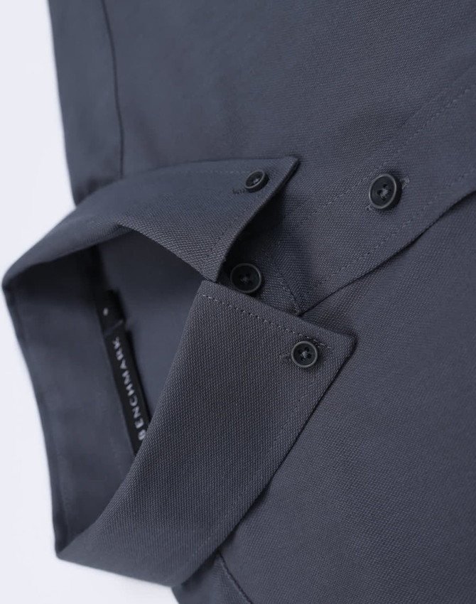 A dark grey cotton blend long-sleeve shirt with a folded collar and button details. It features a logo.