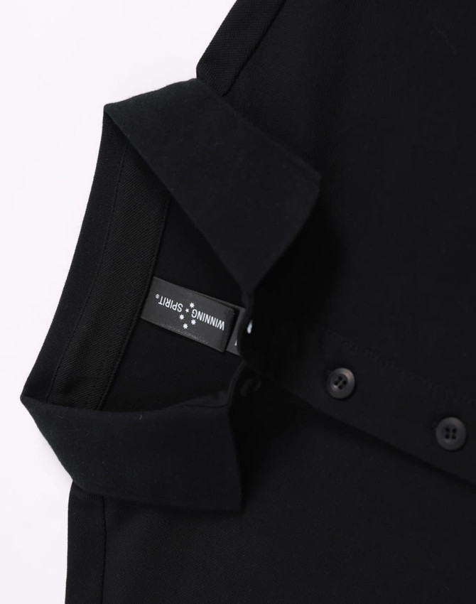 A black ultrafine cotton pique polo featuring buttons and a collar, with a visible brand label.