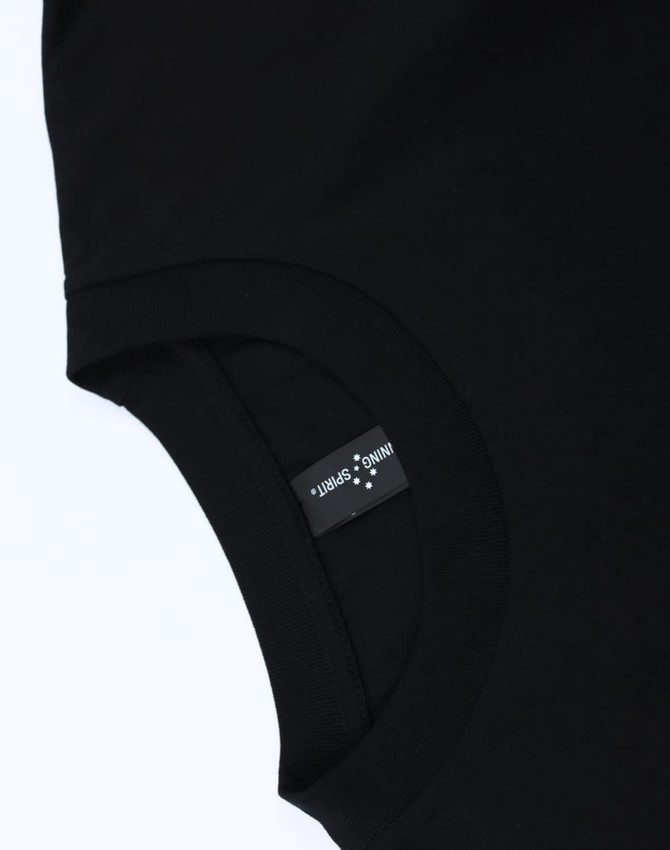 A black unisex heavy cotton oversized tee featuring a tag with branding on the inner neckline.