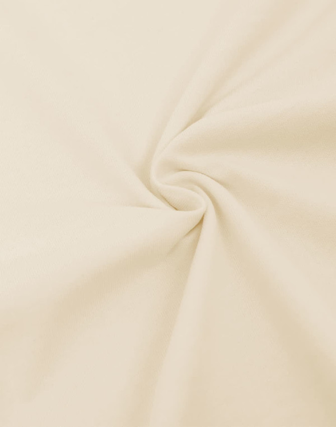 A close-up of light beige fabric, showcasing a smooth, oversized cotton texture with a flowing twist.