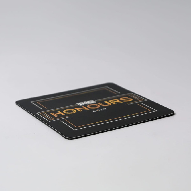 A black deluxe coaster featuring gold accents and a logo, with the word "Honours" prominently displayed.