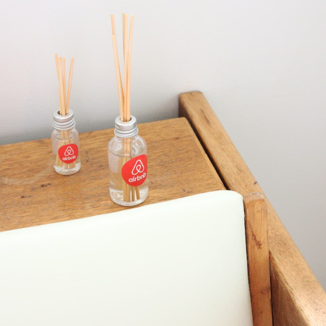 A 10ml reed diffuser in a clear glass bottle with wooden sticks on a wooden surface, featuring a logo.