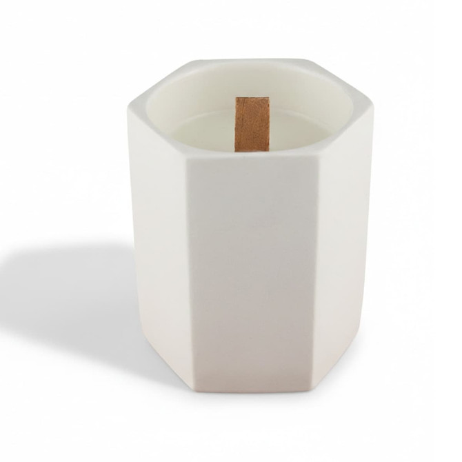 A white hexagonal ceramic candle with a wooden wick placed inside. It has a minimalist design.