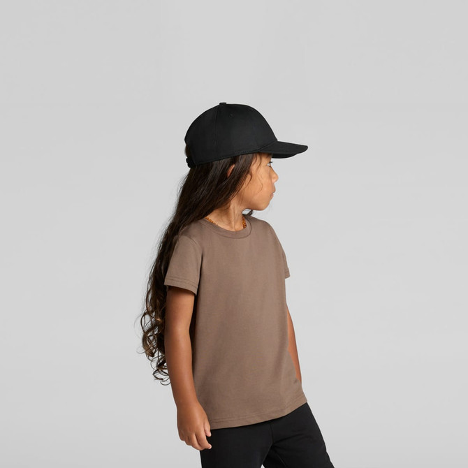 A brown kids' t-shirt displayed on a child, paired with a black cap, featuring long hair and a side profile.