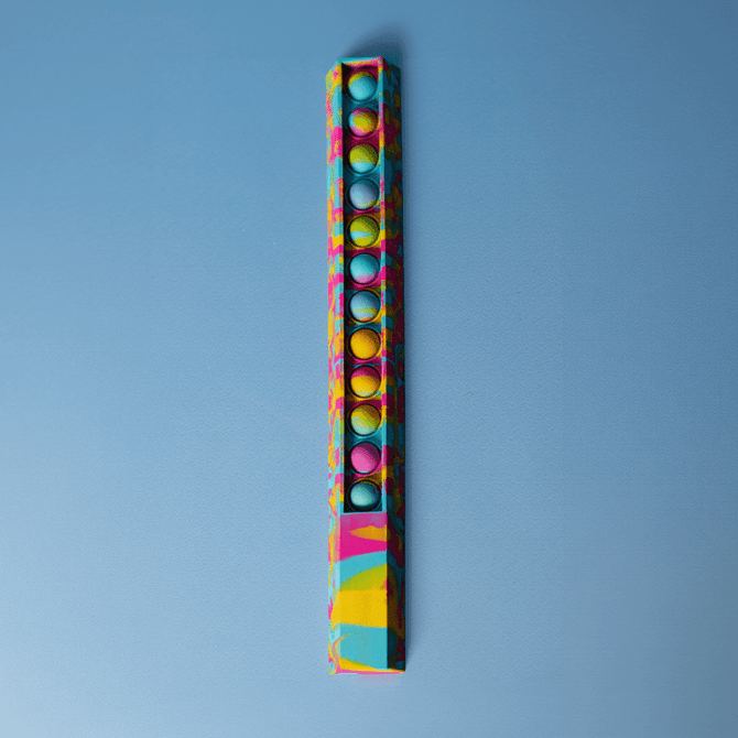 A colourful 30cm popper ruler with a vibrant design and multiple popping buttons along its length, featuring a logo.