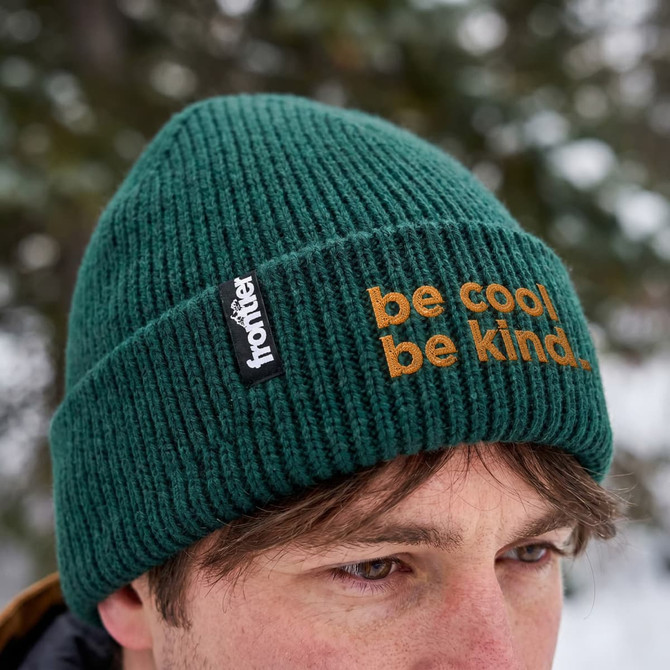 A green ribbed beanie featuring a branding logo and text in orange.