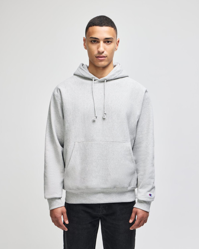 A grey hooded sweatshirt with a front pocket and a logo. Styled with a relaxed fit and drawstrings at the hood.