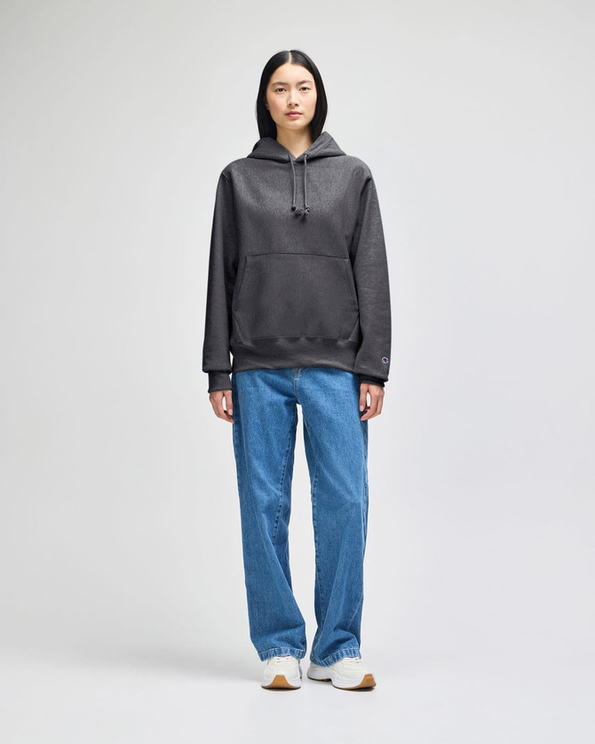A grey pullover hooded sweatshirt with a front pocket, paired with blue jeans and white sneakers.