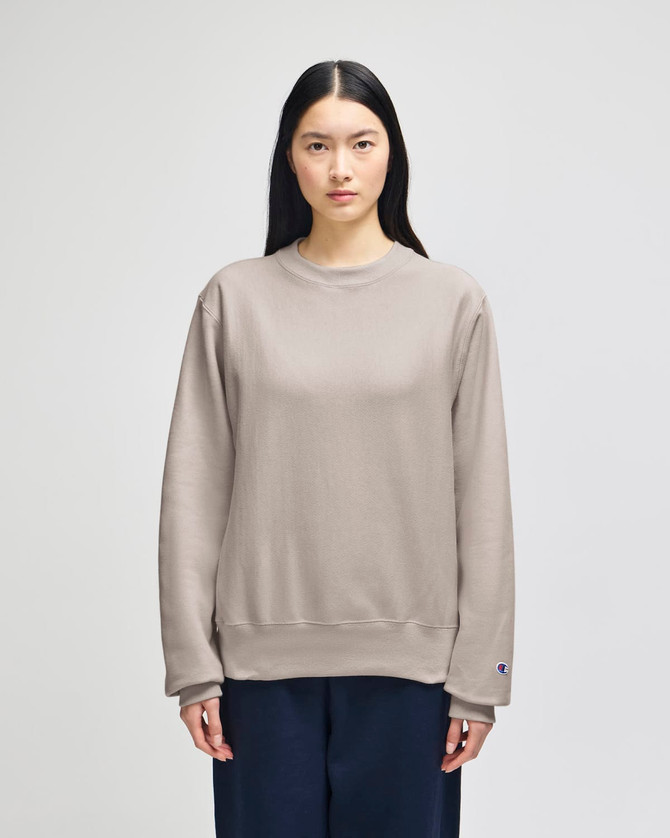 A beige Champion Reverse Weave® adult crew sweatshirt with a relaxed fit and a logo on the sleeve.