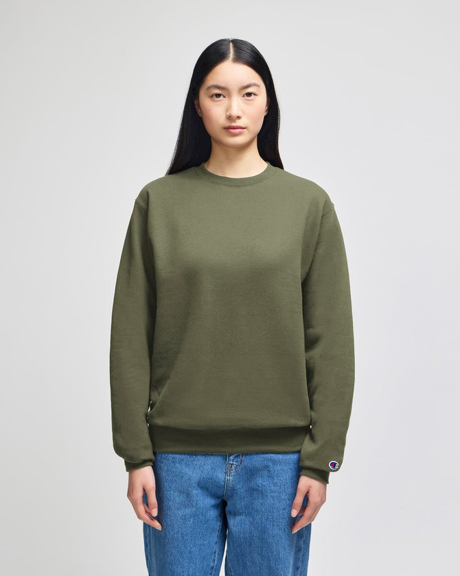 A green Champion Powerblend® adult crewneck sweatshirt displayed on a model, featuring a logo on the sleeve.