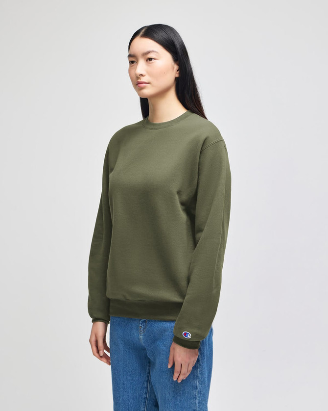 An olive green crewneck sweatshirt displayed on a model, featuring a logo on the sleeve.
