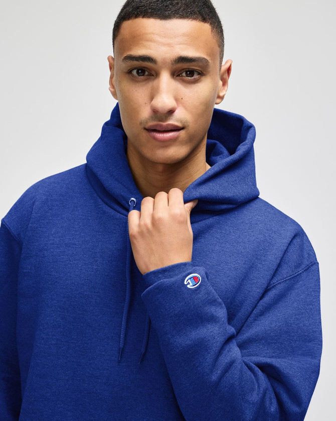 A blue hooded sweatshirt featuring a logo on the sleeve, worn by a model with a neutral expression.