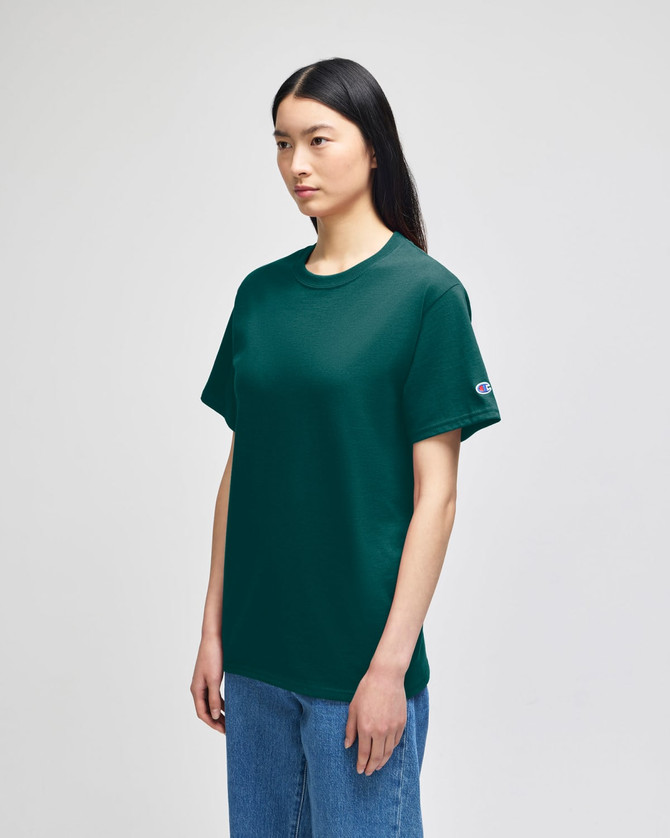 A short-sleeve t-shirt in dark green, featuring a logo on the sleeve, displayed on a model.