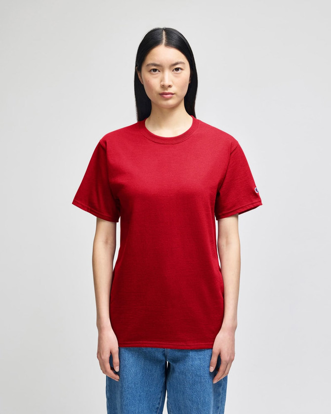 A red Champion adult short-sleeve t-shirt displayed on a model, featuring a logo on the sleeve.