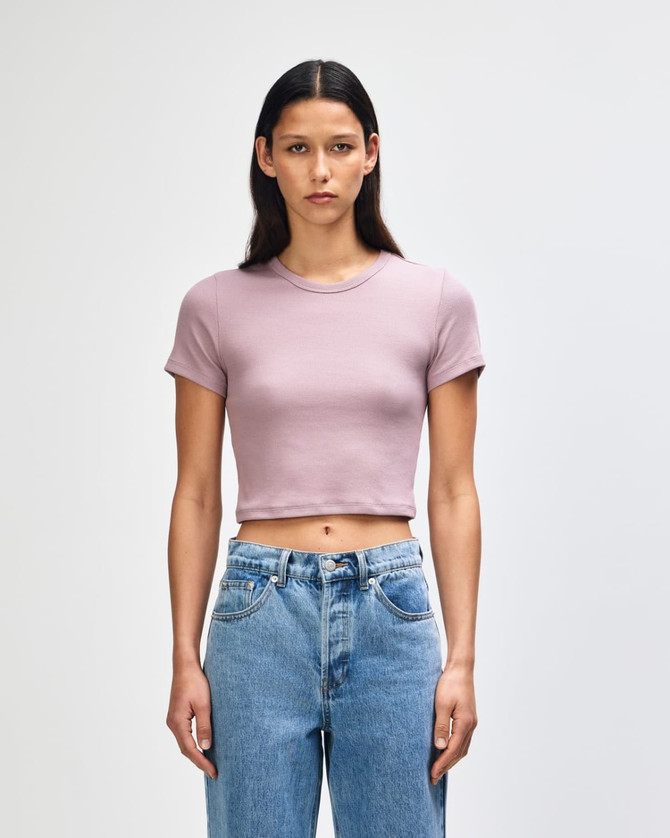 A fitted women's crop T-shirt in light purple, paired with high-waisted blue jeans, featuring a logo.