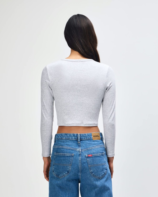 A grey long-sleeve cropped fitted T-shirt with a simple design and a logo on the back, paired with blue jeans.