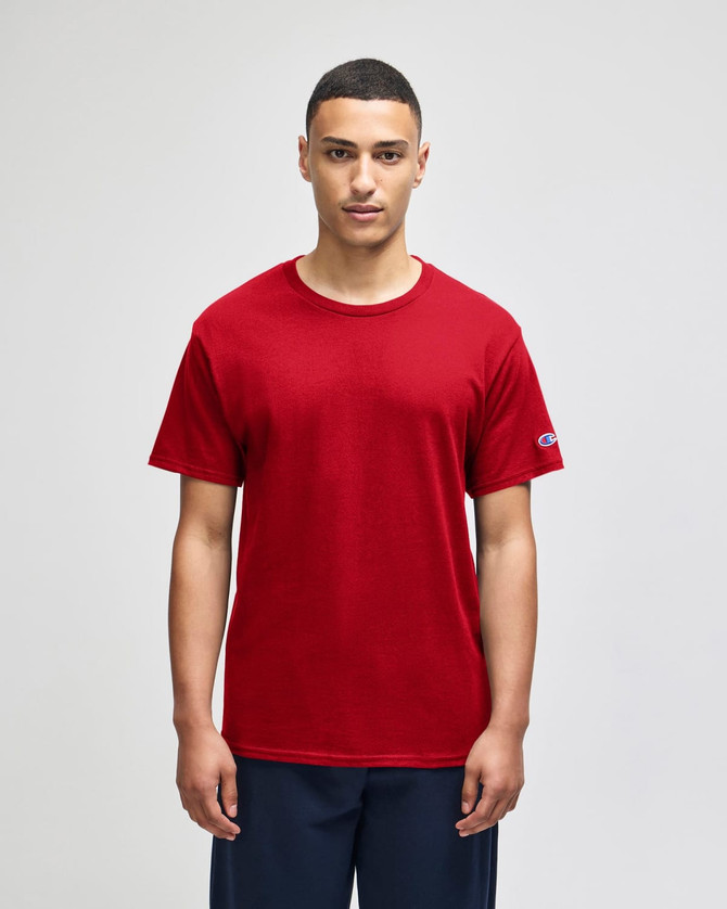 A red Champion adult jersey short sleeve t-shirt displayed on a model with a logo on the sleeve.